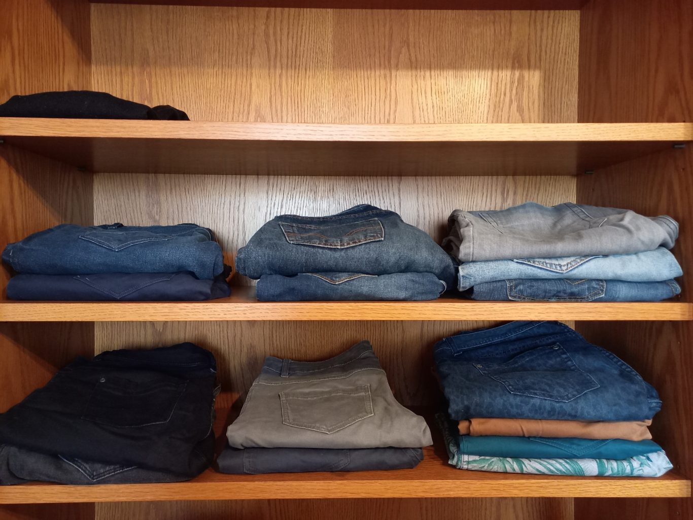 Detail Hosen Regal mit ordentlich gefalteten Kleidungsstücken in verschiedenen Blautönen.
