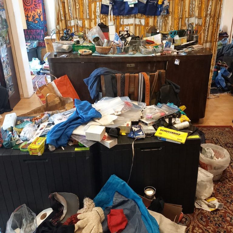 Schreibtisch vorher Unordentliches Zimmer mit mehreren Gegenständen auf dem Boden und einem überladenen Schreibtsich.